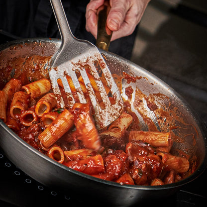 Pasta with red sauce being stirred in a pan with a spatula.