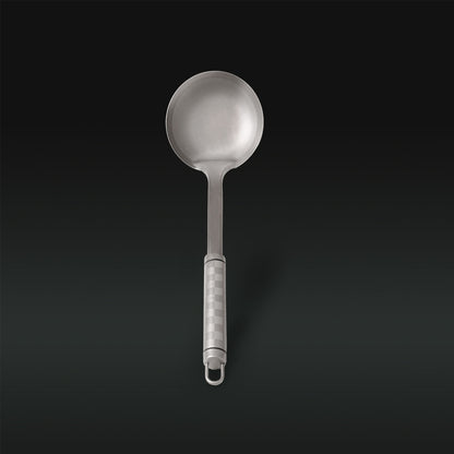 Metallic ladle with a textured handle on a black background