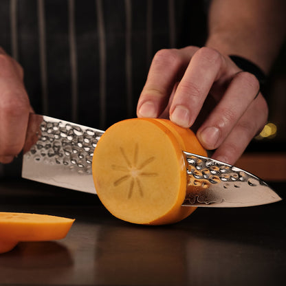 Person grating a carrot with a metal grater on a dark surface