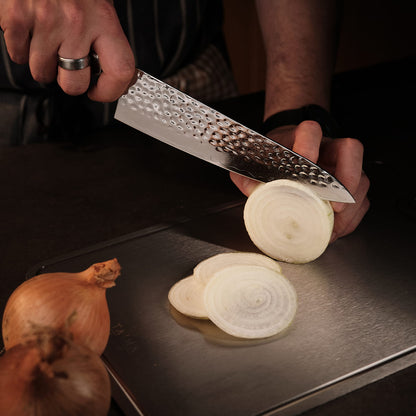 Person slicing an onion on a cutting board with a chef's knife.