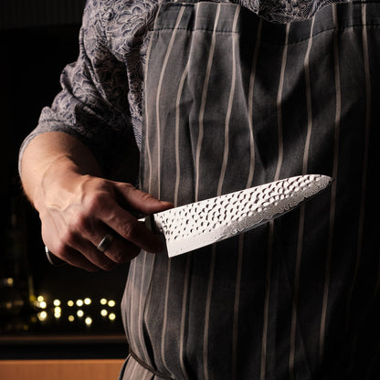 Person wearing a striped apron holding a chef's knife