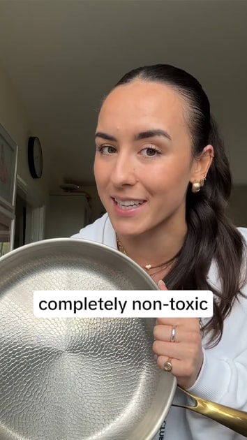 Person holding a non-stick frying pan with 'completely non-toxic' text overlay.