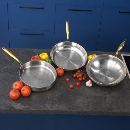 Three Titanium cookware items on a kitchen counter with vegetables.