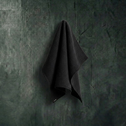 Dark gray towel hanging on a textured green wall