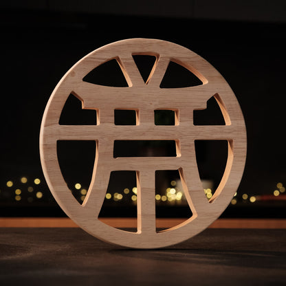 Wooden decorative item with cut-out design on a dark background with blurred lights