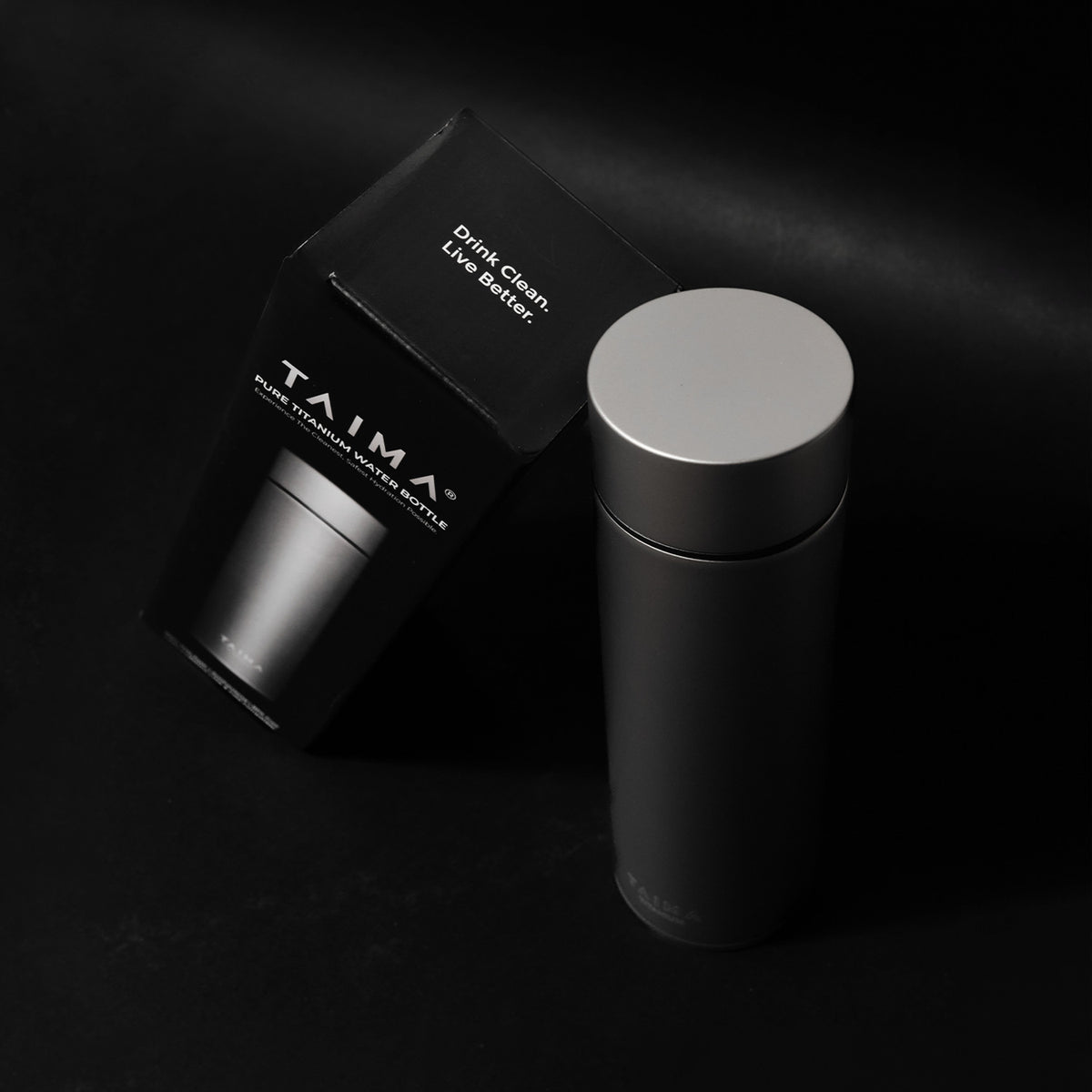 Black Taima water bottle with packaging on a dark background