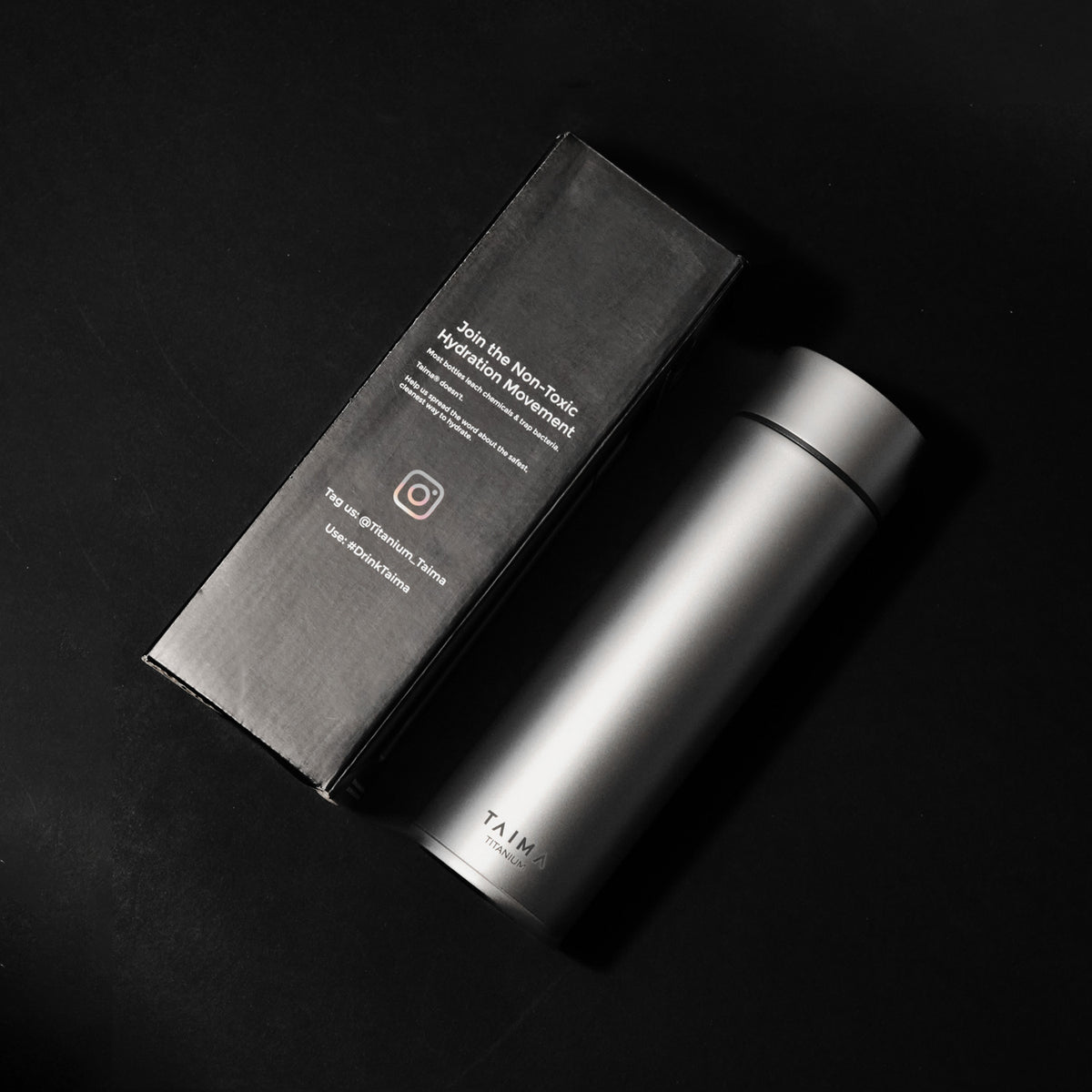 Titanium thermos bottle with black box on a dark background